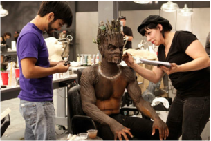 Makeup artists apply a creature makeup fro a film shoot.