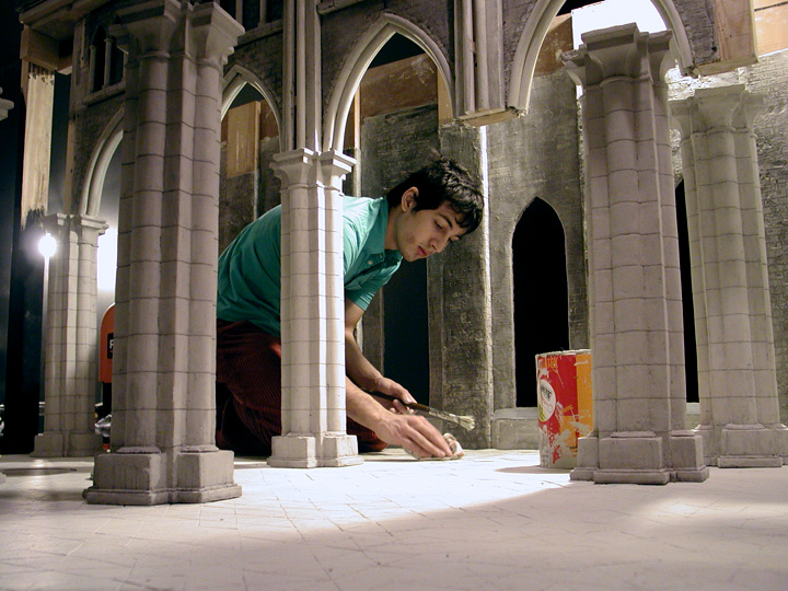 A crew member works on final touches of a film set scale model