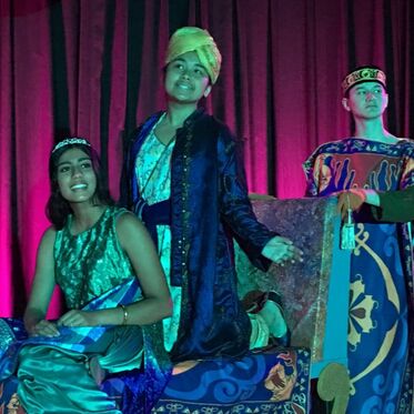 Student actors portray Jasmine, Aladdin, and the magic carpet.