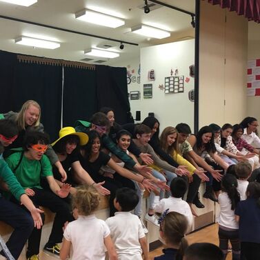 High school performers give high fives to elementary school audience members. 