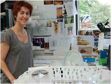 A production designer stands among designs and scale models 